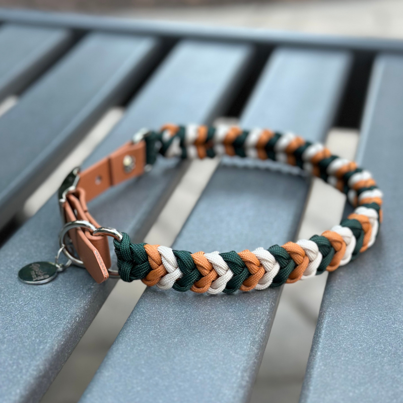 Dog collar with braided design in green, yellow, and white on a metal stand.