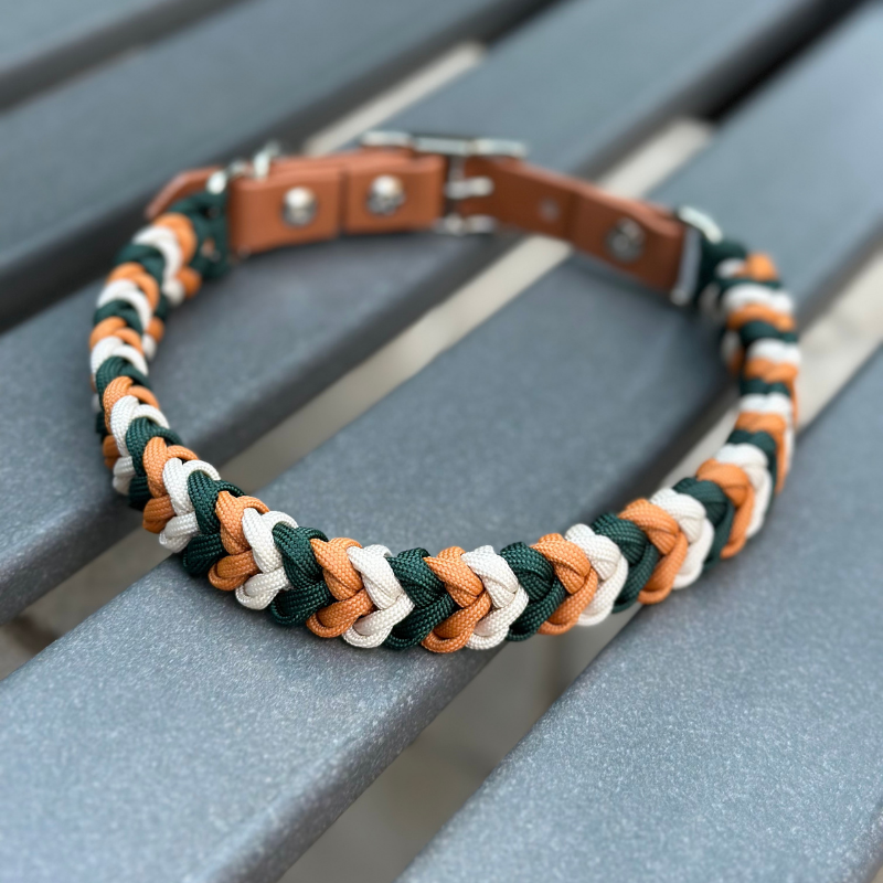 Dog collar with braided design in green, yellow, and white on a metal stand.