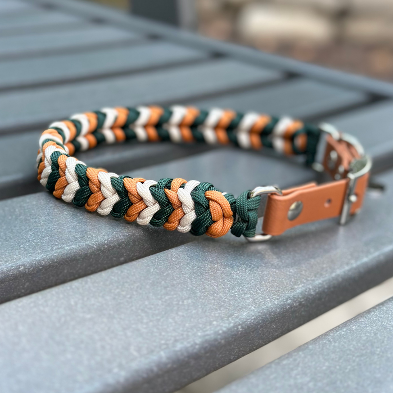 Dog collar with braided design in green, yellow, and white on a metal stand.