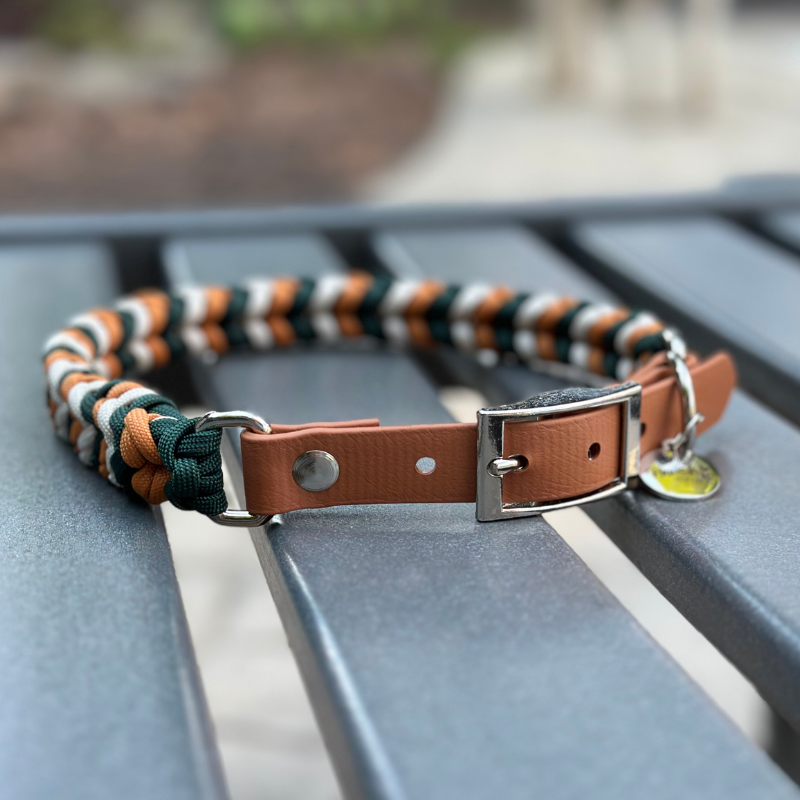 Dog collar with braided design in green, yellow, and white on a metal stand.
