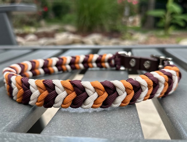 Multicolored braided dog collar on a metal surface with a blurred natural background