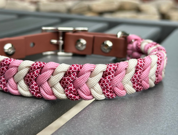 Braided pink and white dog collar on a metal surface with blurred background