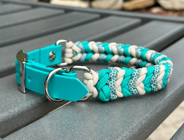 Teal and white braided dog collar on a gray surface