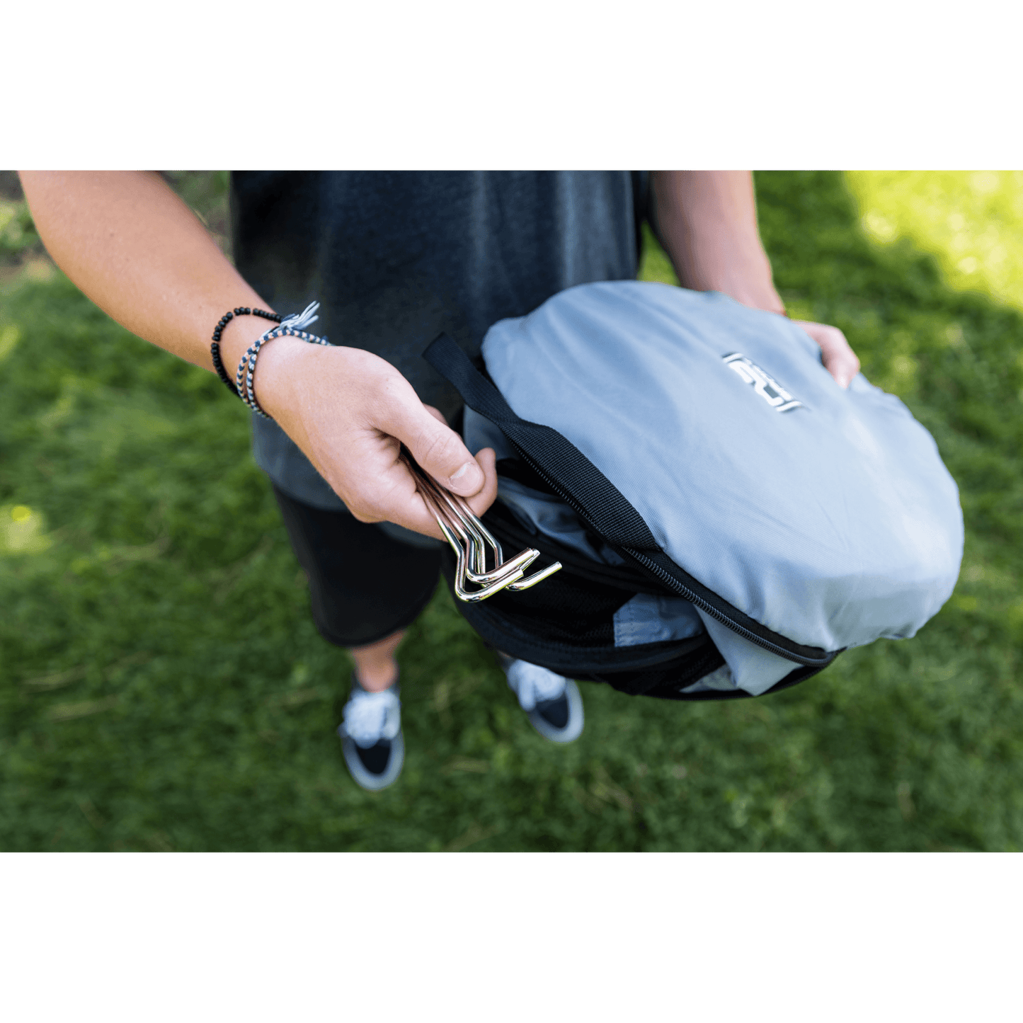 Person holding a gray backpack with a green background