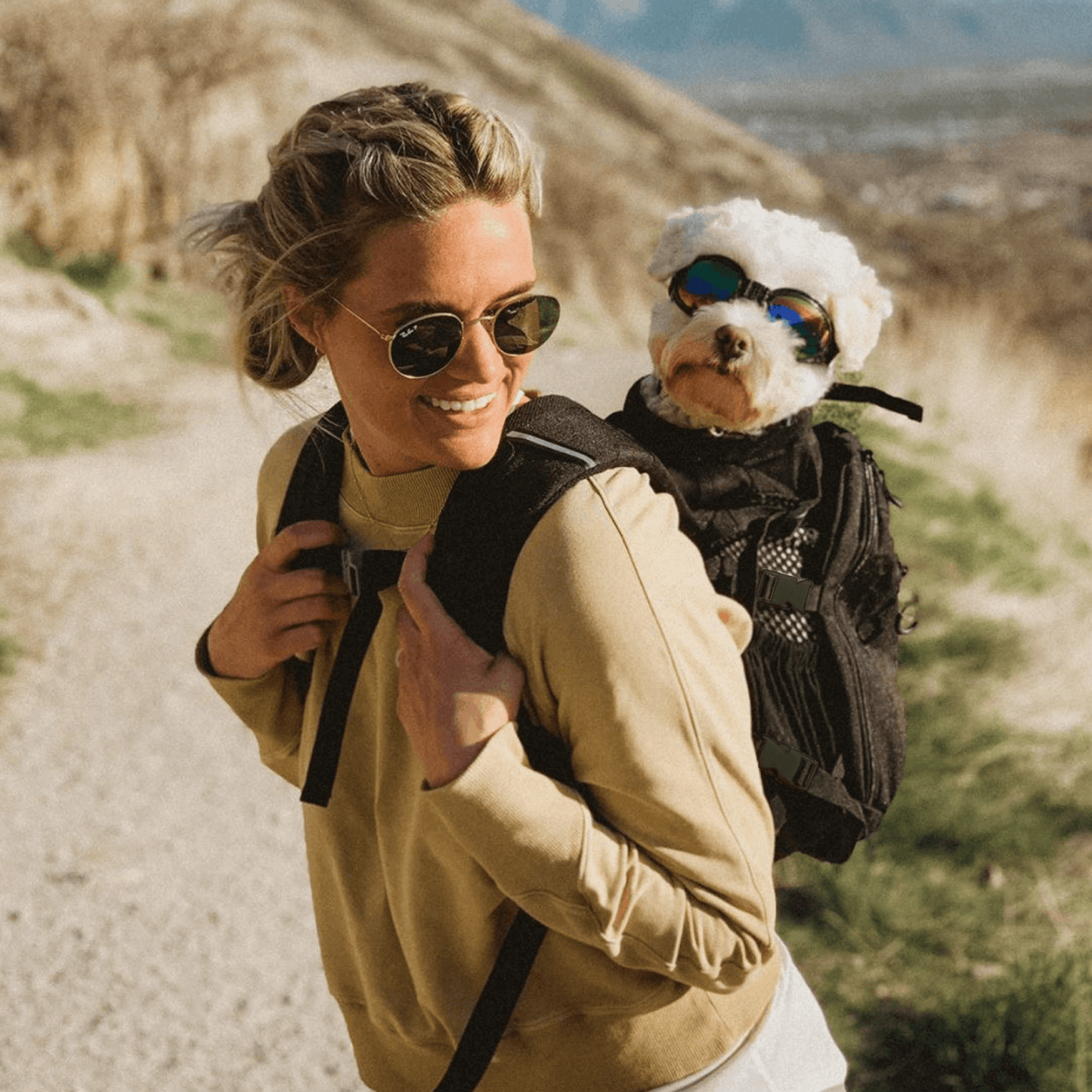Woman hiking with a dog in a backpack on a mountain trail