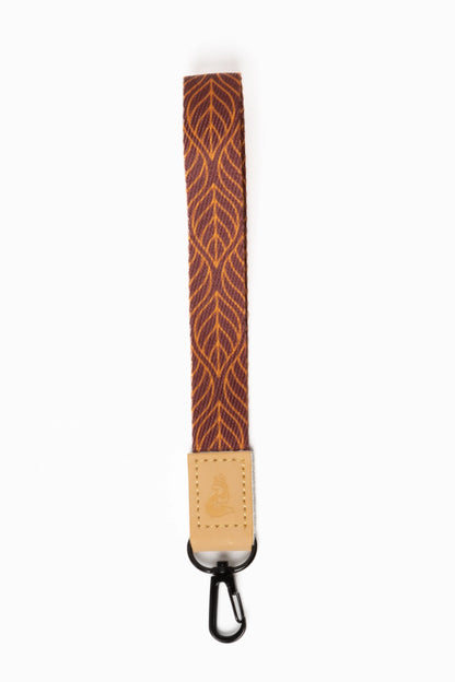 Brown strap with geometric pattern and metal clip on a white background