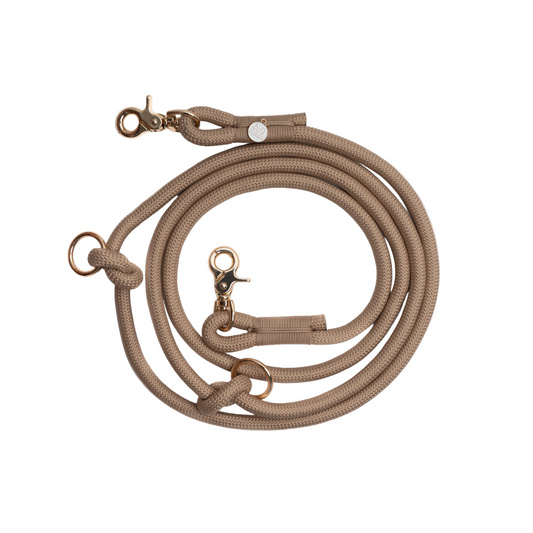 Beige dog leash with brass hardware on a white background