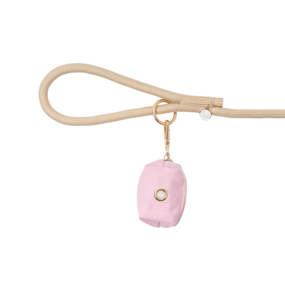 Pink pouch with gold ring on a beige strap against a white background