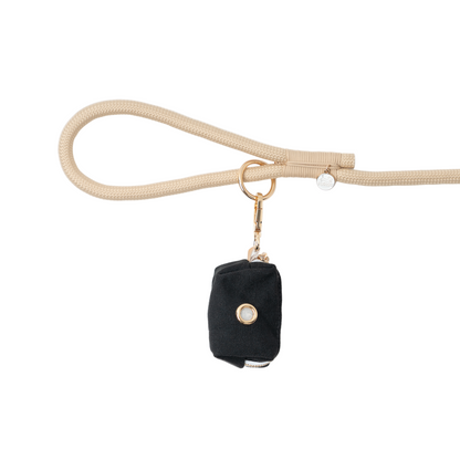 Black pouch with gold clasp on a beige leash against a white background