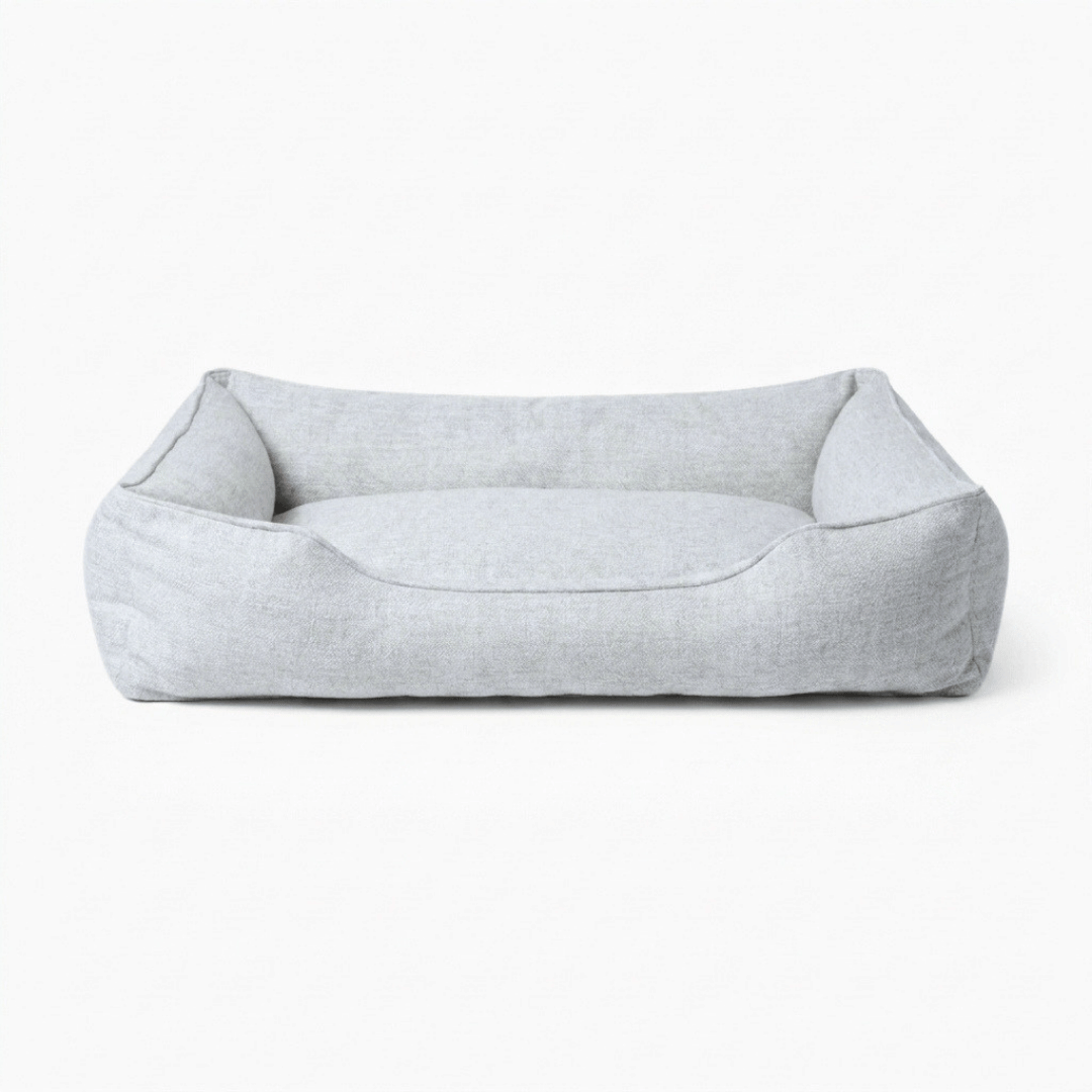 A light gray fabric pet bed with a low, open-top rectangular design and raised sides, shown against a plain white background.