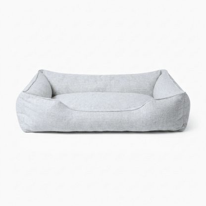 A light gray fabric pet bed with a low, open-top rectangular design and raised sides, shown against a plain white background.