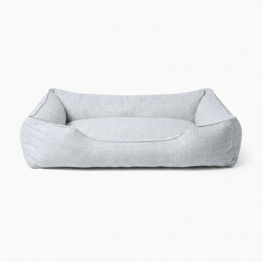 A light gray fabric pet bed with a low, open-top rectangular design and raised sides, shown against a plain white background.