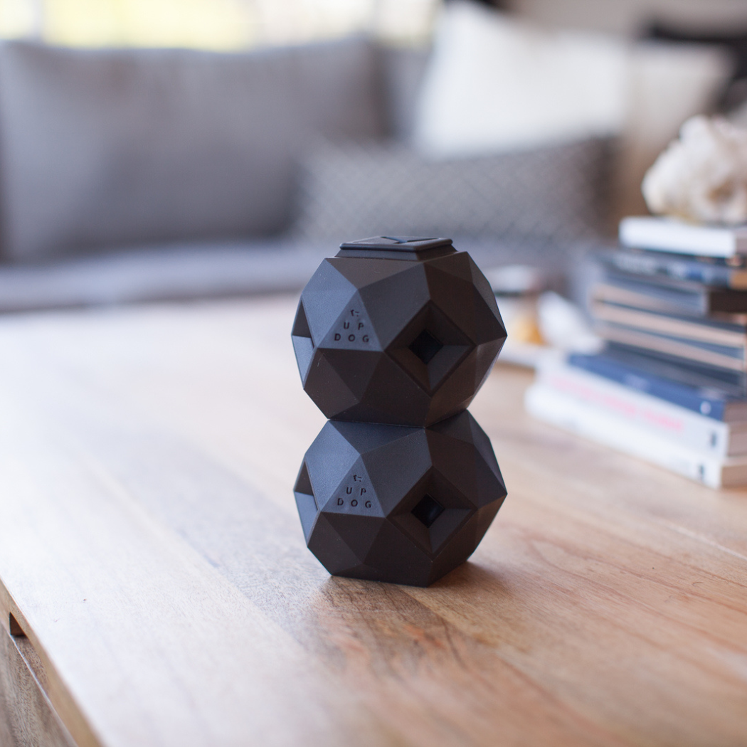 Black geometric-shaped speaker on a wooden surface with a blurred background
