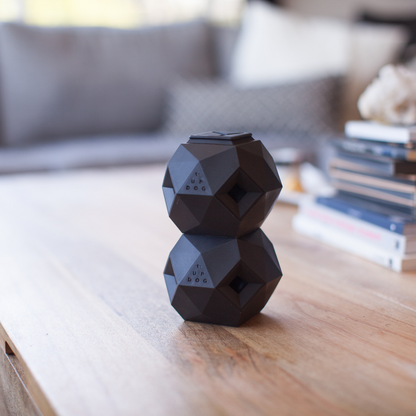 Black geometric-shaped speaker on a wooden surface with a blurred background