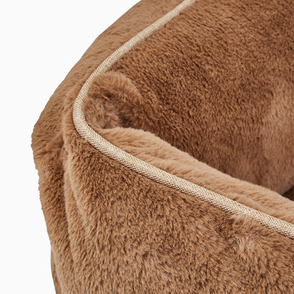 Close-up of a brown plush pet bed with a white trim on a white background