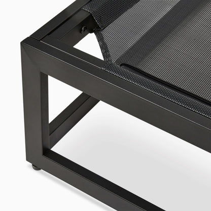 Close-up of a black metal chair with a textured black cushion on a white background