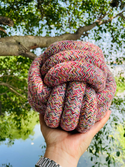 Colorful knotted rope dog toy held in a hand with a natural background