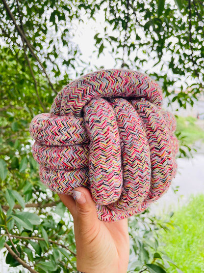 Hand holding a colorful knotted rope against a natural background