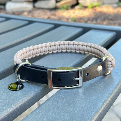 Dog collar with a light tan braided design and black biothane strap  on a blue surface.