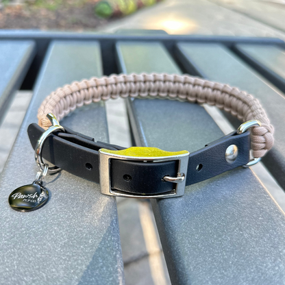 Dog collar with a light tan braided design and black biothane strap  on a blue surface.