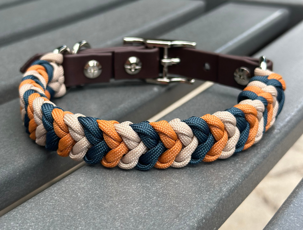 Dog collar with braided design in brown, orange, and blue on a metallic surface