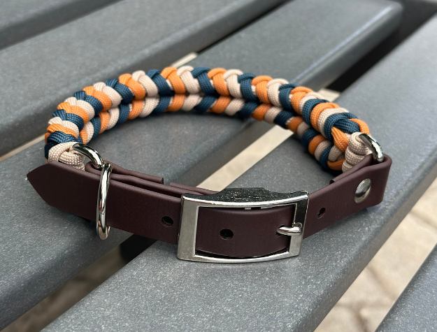 Dog collar with brown leather strap and colorful braided design on a gray surface
