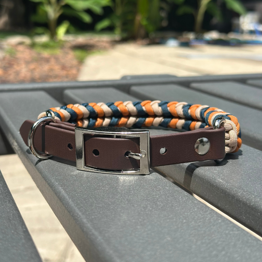 Dog collar with braided design and brown leather strap on a metal surface