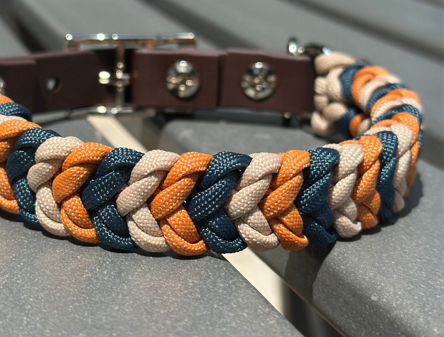 Dog collar with braided design in blue, orange, and beige on a gray surface.