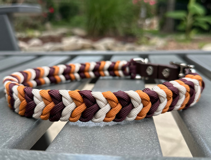 Multicolored braided dog collar on a metal surface with a blurred natural background