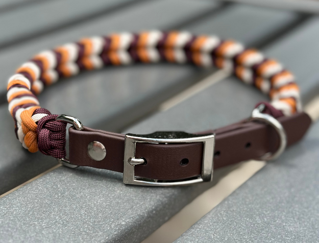 Dog collar with striped pattern and brown leather section on a wooden surface