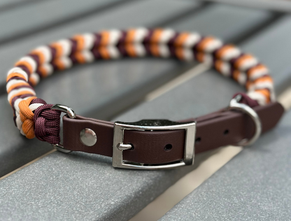 Dog collar with striped pattern and brown leather section on a wooden surface