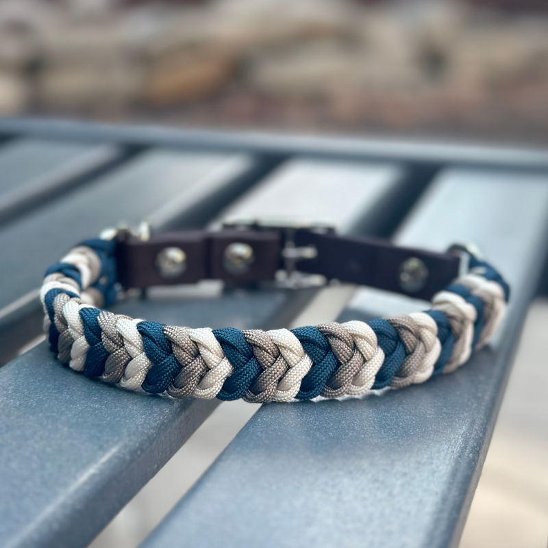Braided dog collar with blue and gray pattern on a metal surface