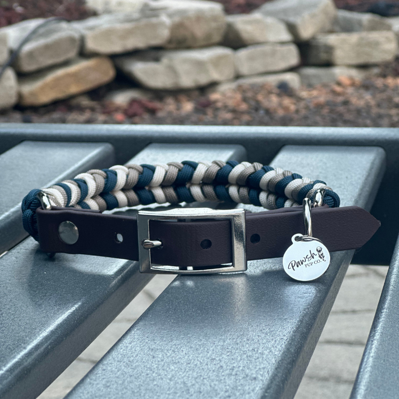 Dog collar with braided design and branded tag on a metal surface.