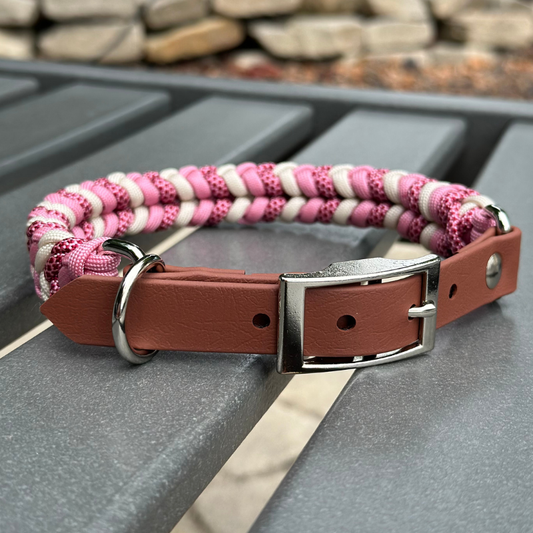 Dog collar with pink and white braided design on a metal surface