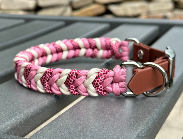 Dog collar with pink and white braided design on a metal surface