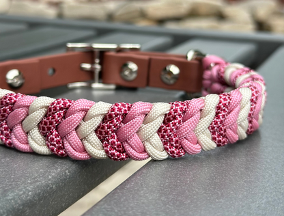 Braided pink and white dog collar on a metal surface with blurred background