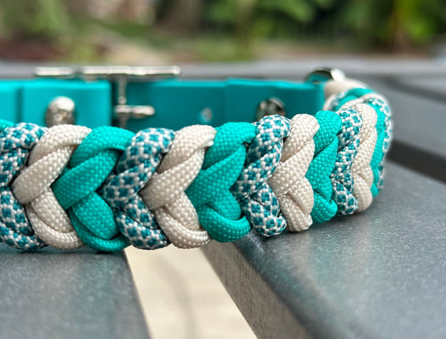 Close-up of a braided teal and white dog collar on a metal surface.