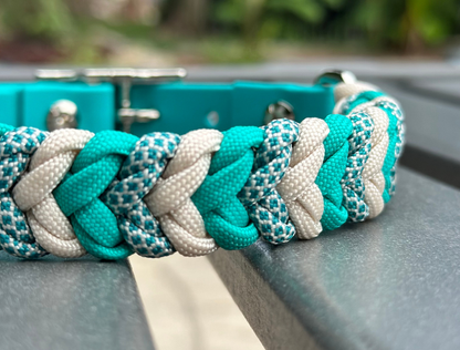 Close-up of a braided teal and white dog collar on a metal surface.