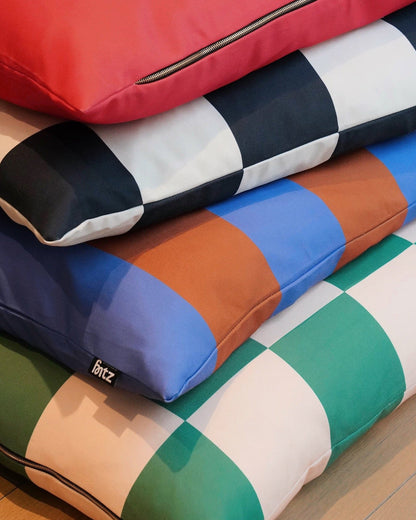 Colorful checkered dog bed pillows stacked on a wooden surface