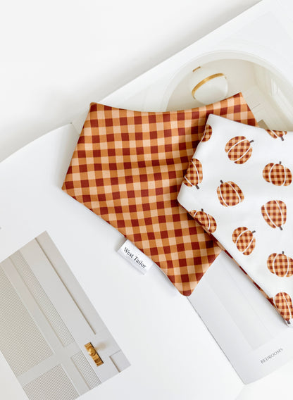 Checkered and pumpkin-patterned bandana on a white surface