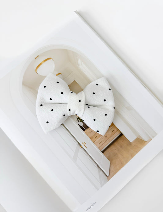 White polka dot bow on a white surface