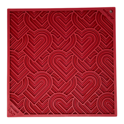 Red textured dog lick mat square with heart patterns on a beige background