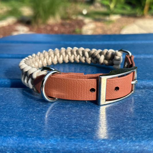 Dog collar with braided design and brown leather section on a blue surface
