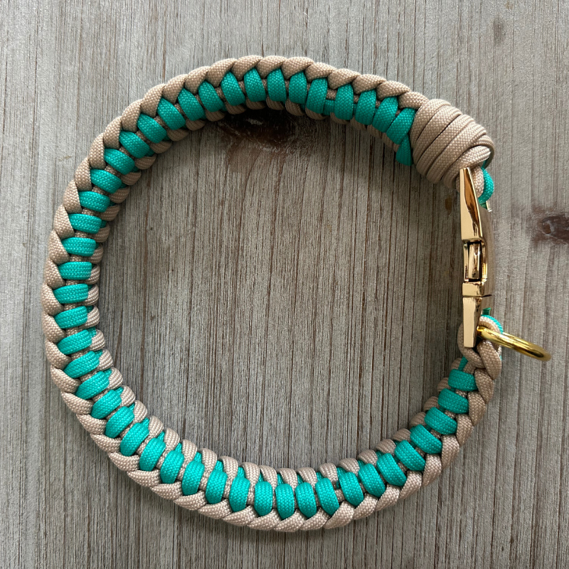 Paracord dog collar with turquoise and beige pattern on a wooden surface