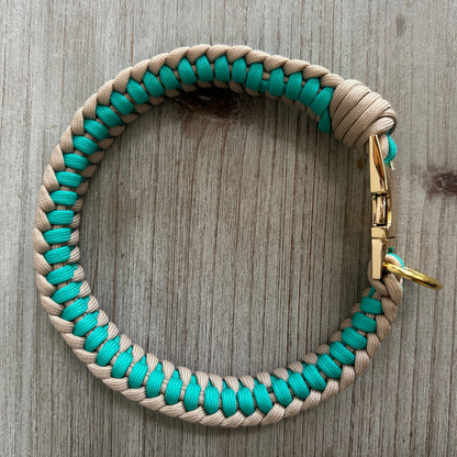 Paracord dog collar with turquoise and beige pattern on a wooden surface