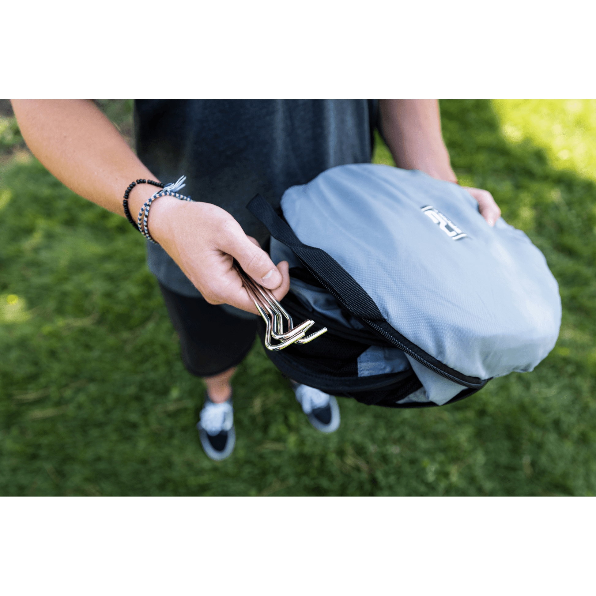 Person holding a gray backpack with a green background