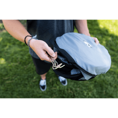 Person holding a gray backpack with a green background