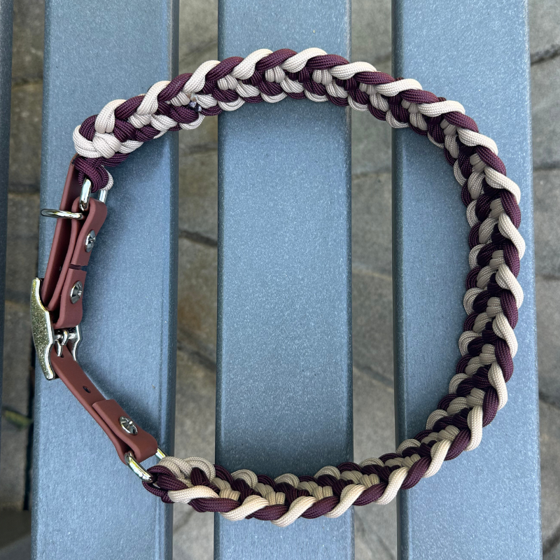 Dog collar with braided design in burgundy and light tan with medium brown BioThane strap on a gray surface outdoors.
