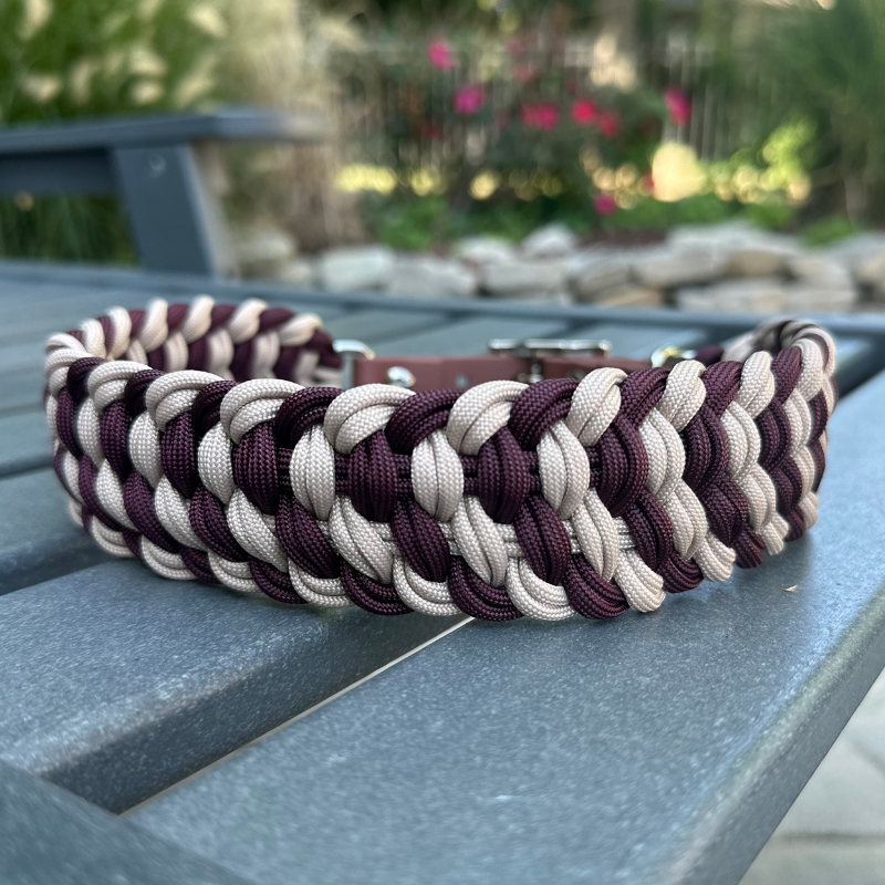 Dog collar with braided design in burgundy and light tan with medium brown BioThane strap on a gray surface outdoors.