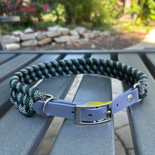 Dog collar with hunter green and silver diamond braided design and gray BioThane strap on a gray surface with a garden background.